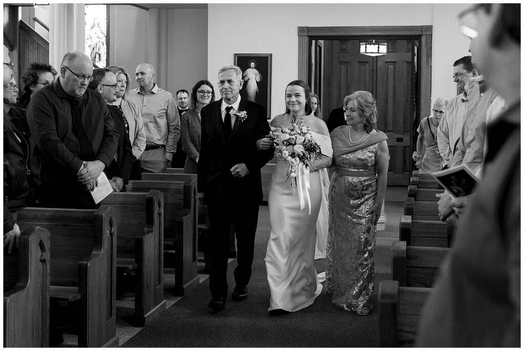 Parents walking the bride down the aisle of Catholic Church