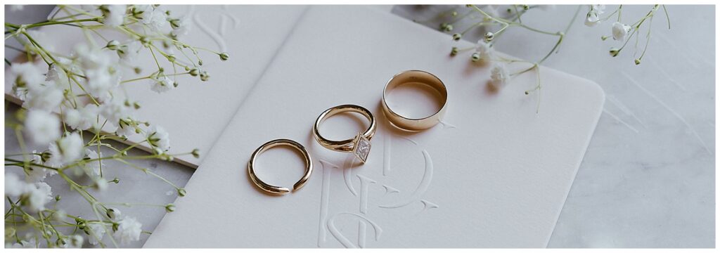 Gold wedding bands on white vow books