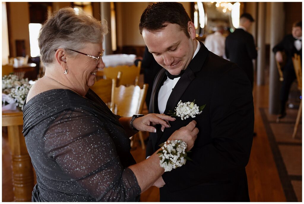 Mother of the bride pinning flowers on the groom
