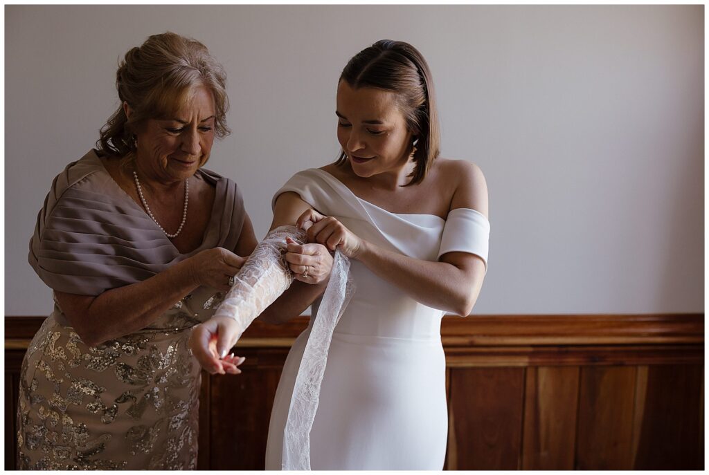 Mother of the bride helping her get her lace sleeves in place